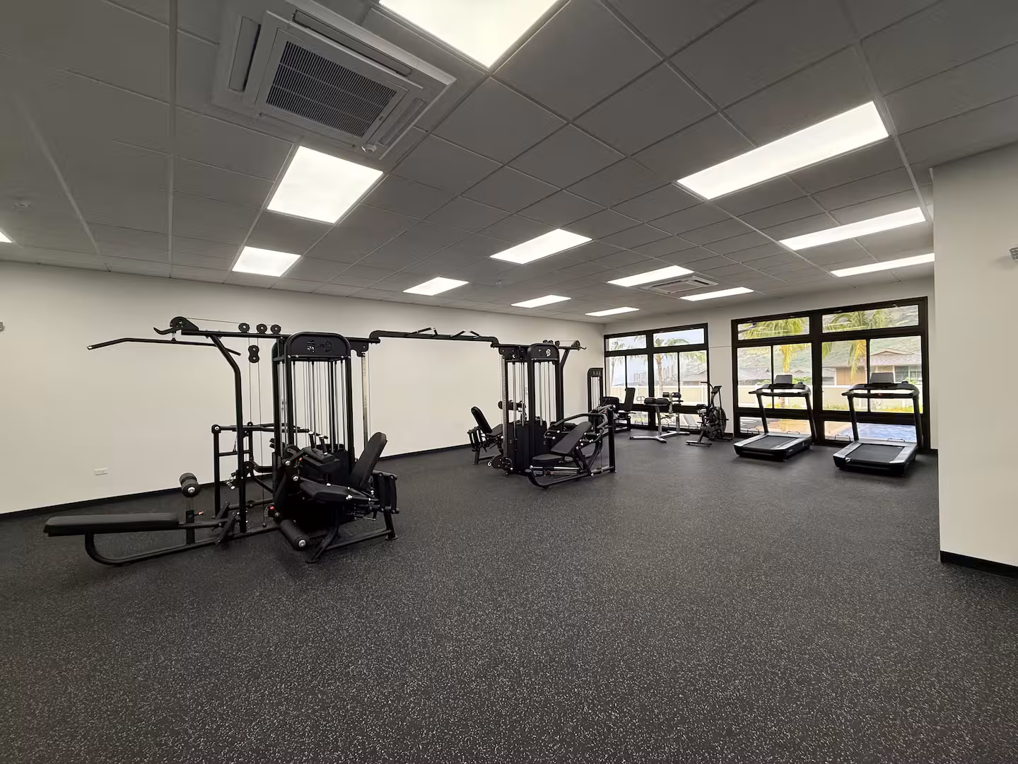 Community fitness room with weight machines, treadmills and floor-to-ceiling windows