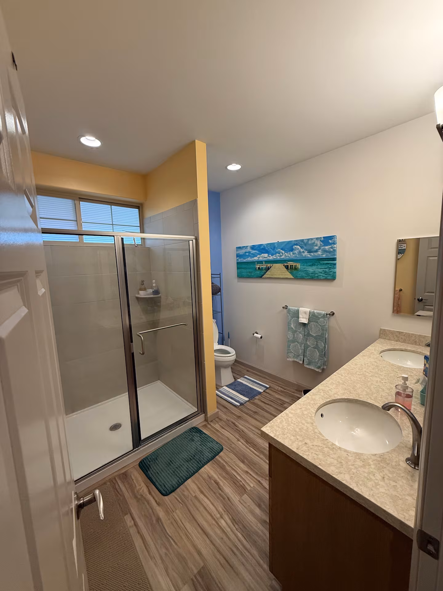 Bathroom with a double vanity, walk-in shower and coastal artwork