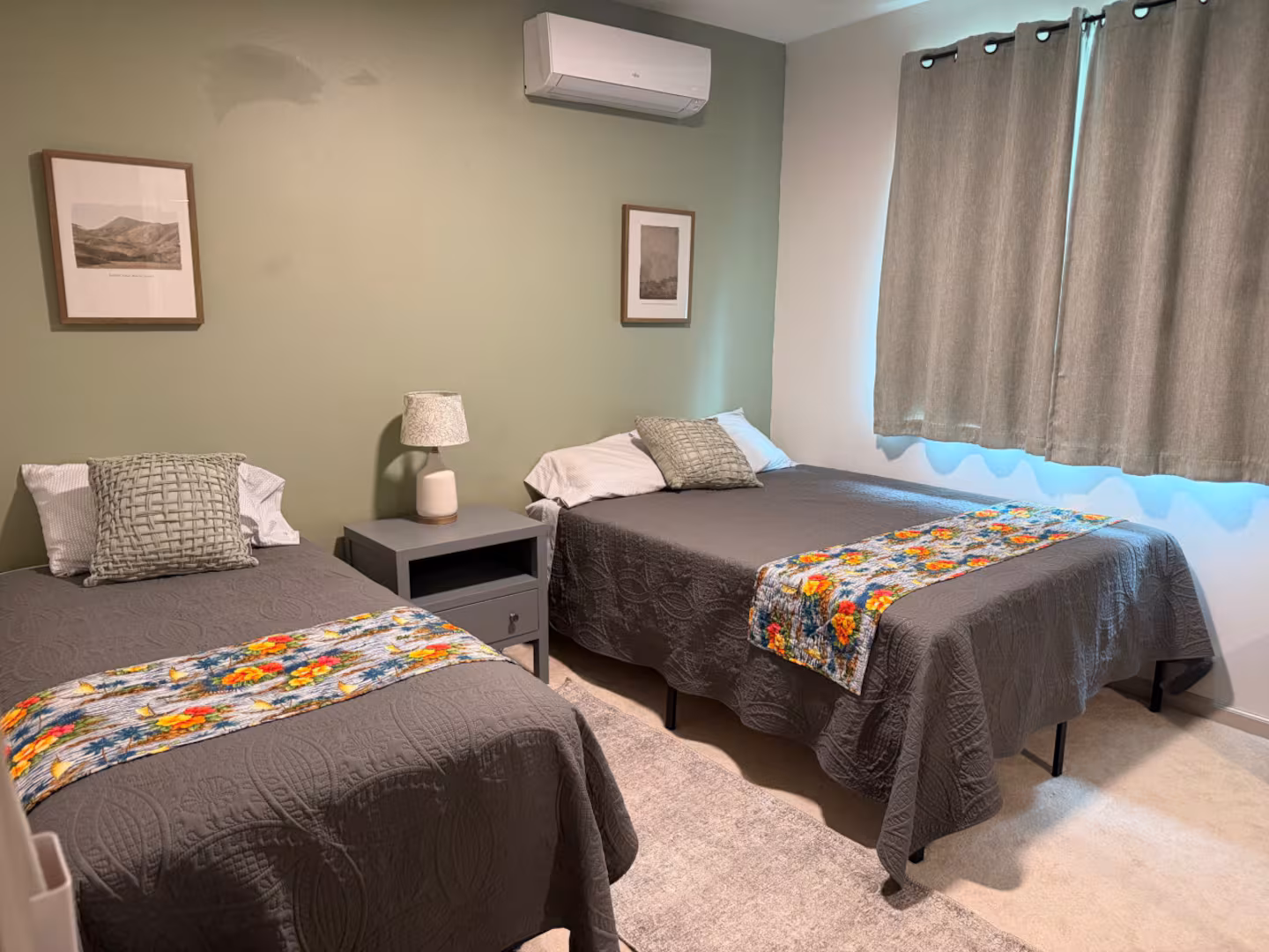 Second bedroom with two twin beds, a shared nightstand and a sage green wall
