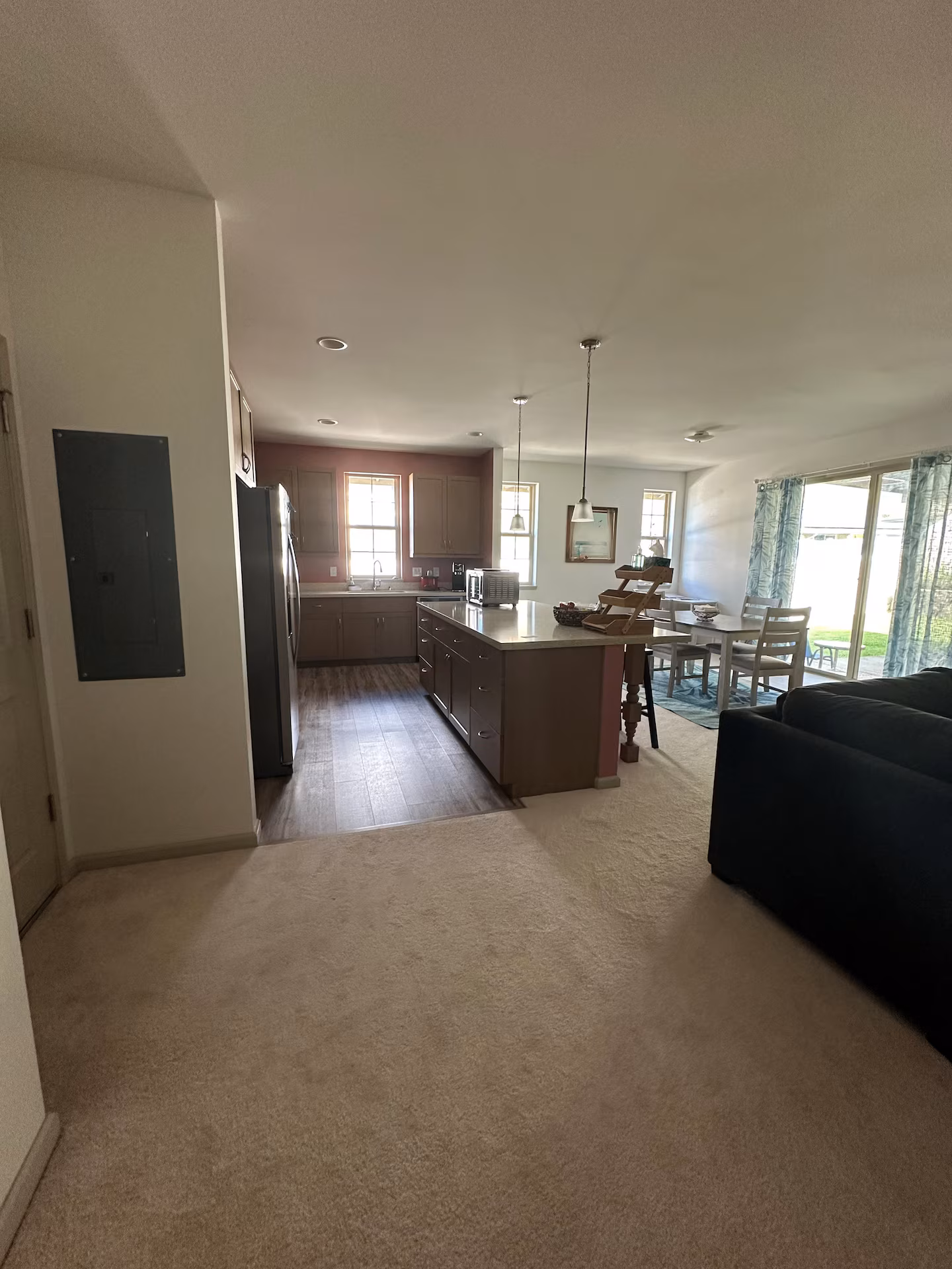 Kitchen seen from the living room, with the island, stainless fridge and lanai doors beyond