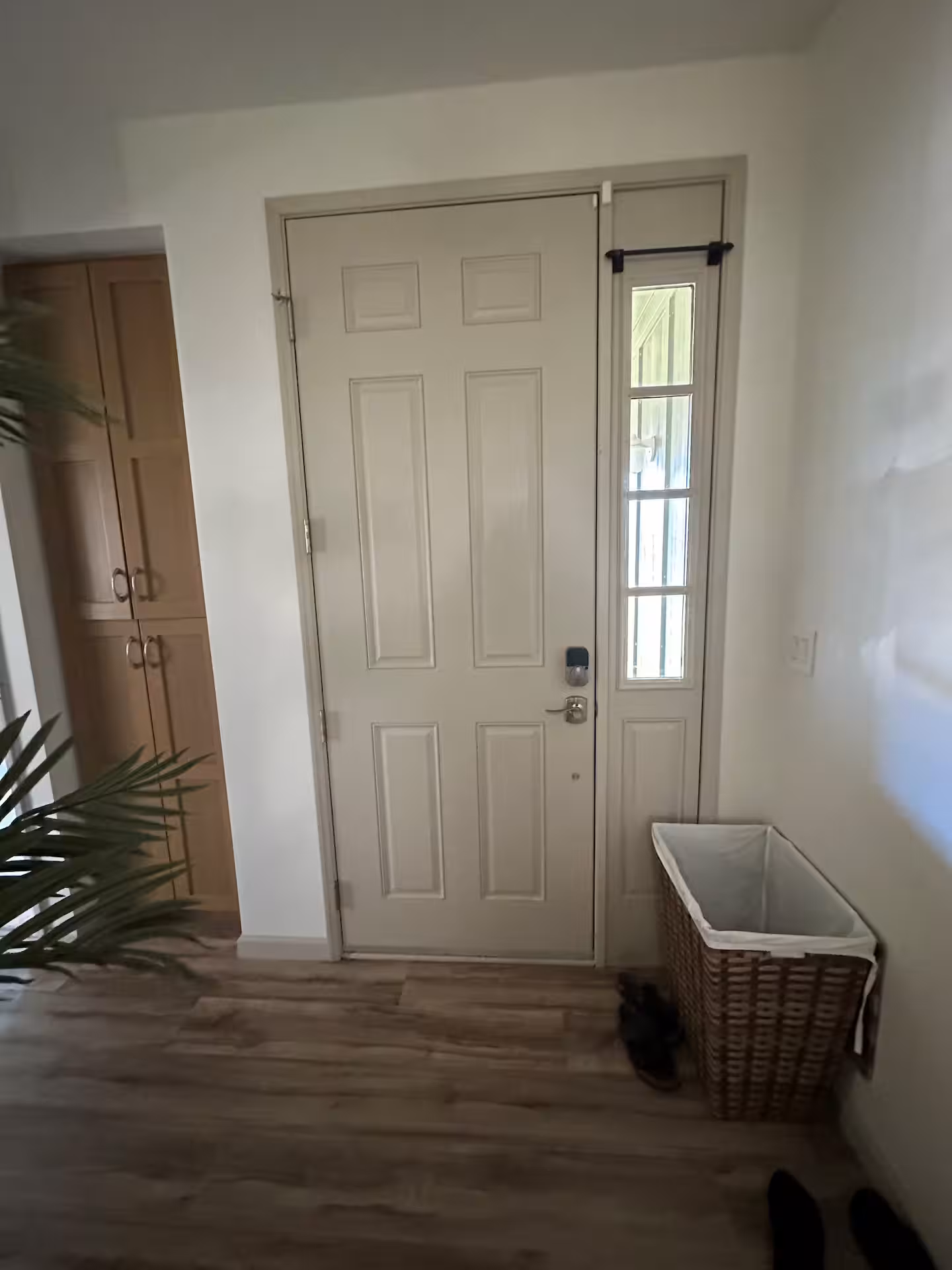 Entry hall with the front door, a laundry basket and a tall storage cupboard