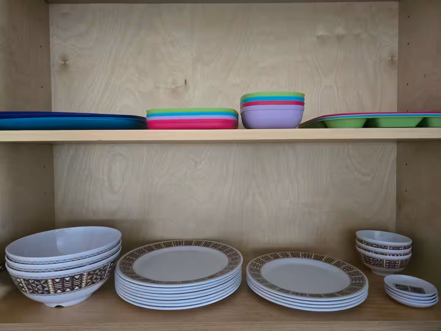 Kitchen cupboard stocked with plates, bowls and colourful children's tableware