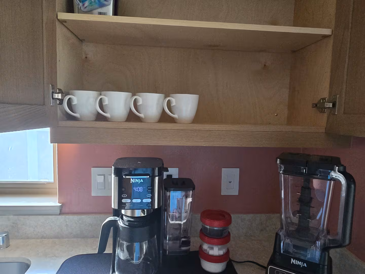 Coffee maker, blender and mugs on the kitchen counter