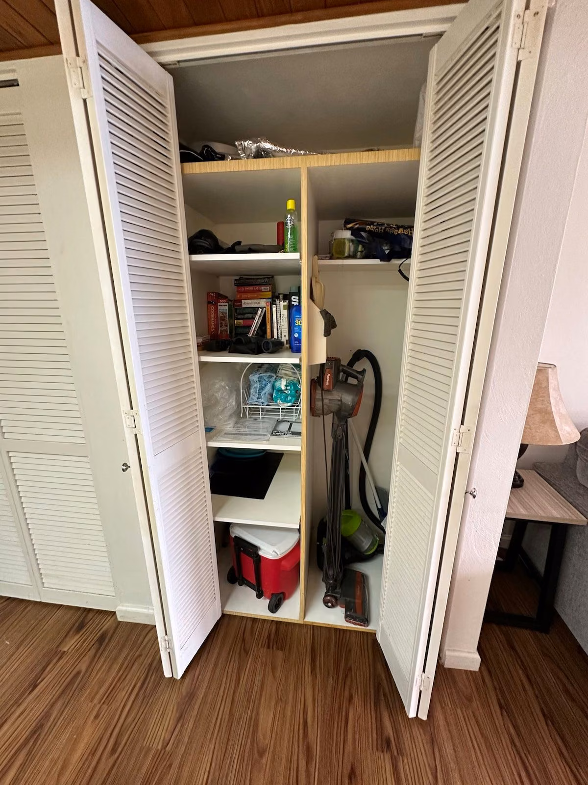 Storage closet with beach gear, board games, a cooler and a vacuum