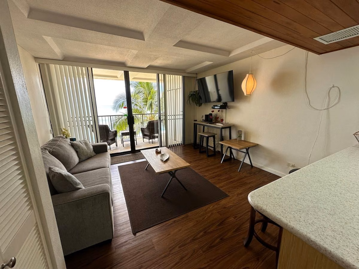 Open-plan living area with the lanai doors ahead and the kitchen breakfast bar to the right