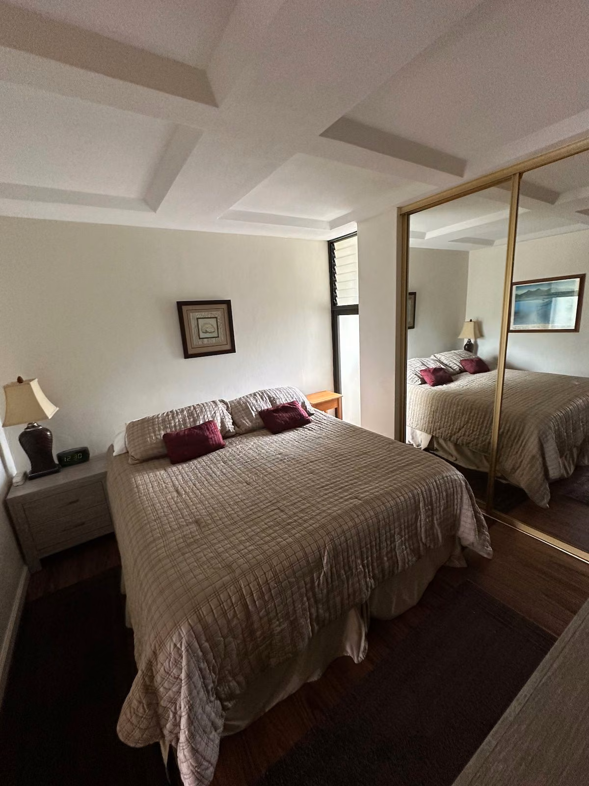 Bedroom with a king bed, bedside lamp and mirrored closet doors