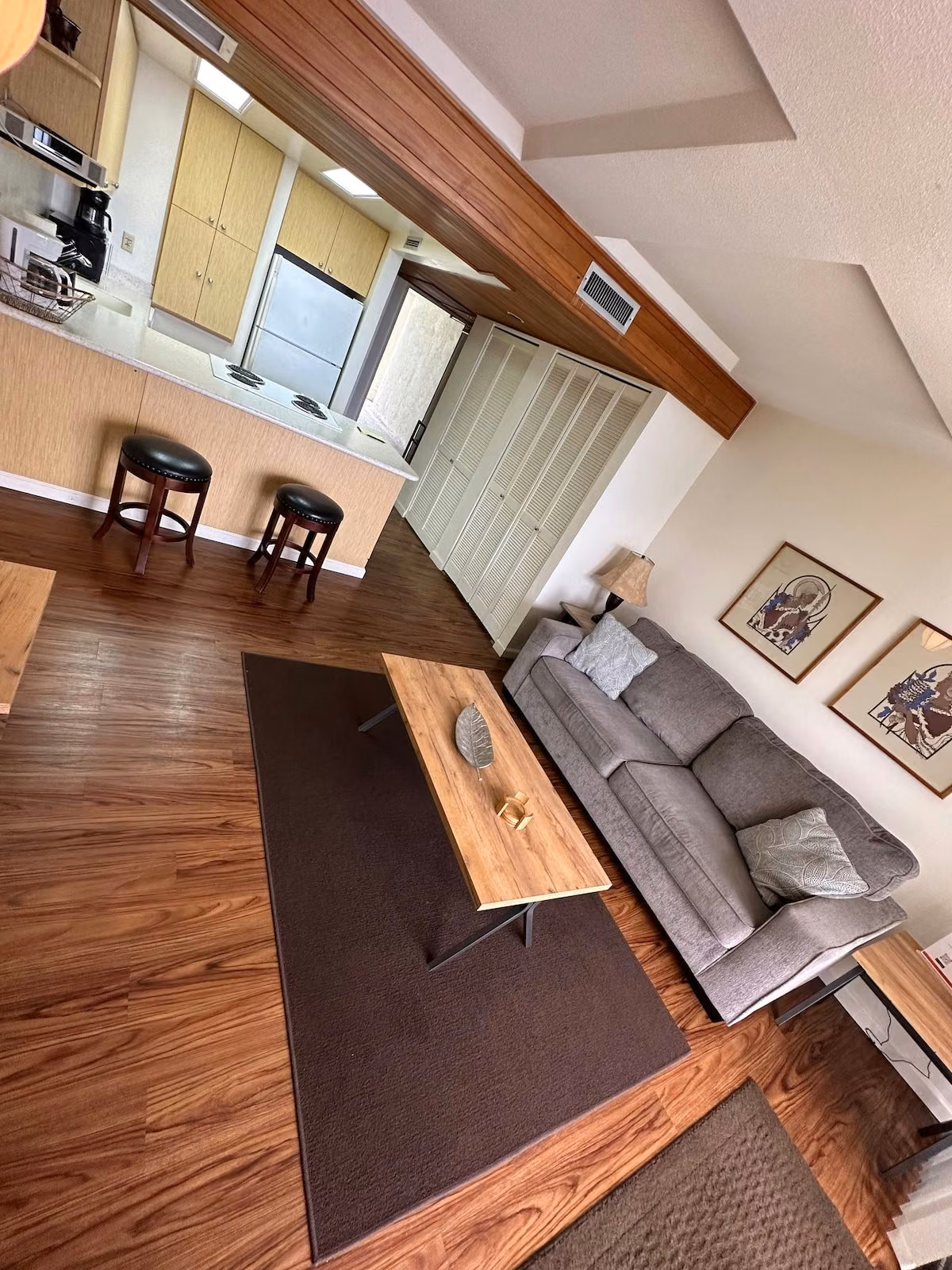 Living room seen from above, showing the sofa, coffee table and the kitchen bar with two stools