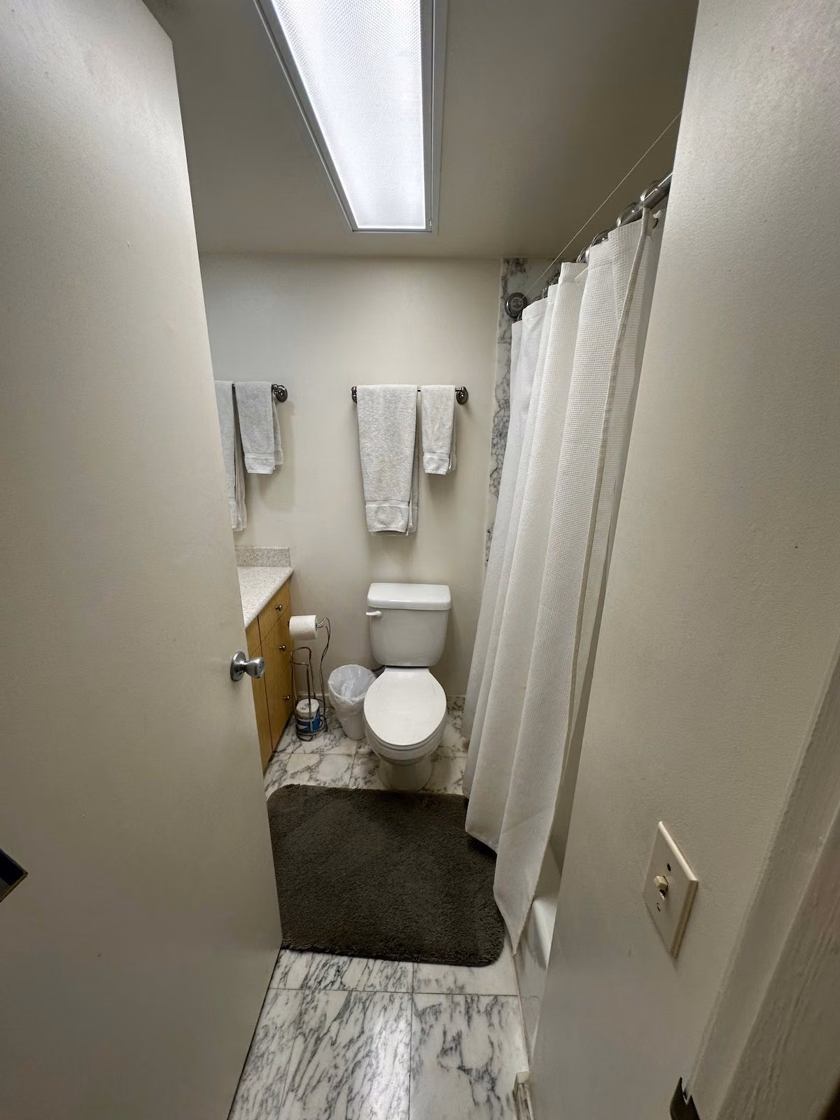 Bathroom with a marble-tiled shower, toilet and folded towels
