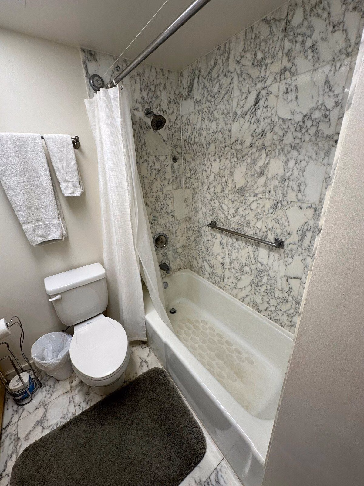 Bathroom with a bathtub and shower in marble tile