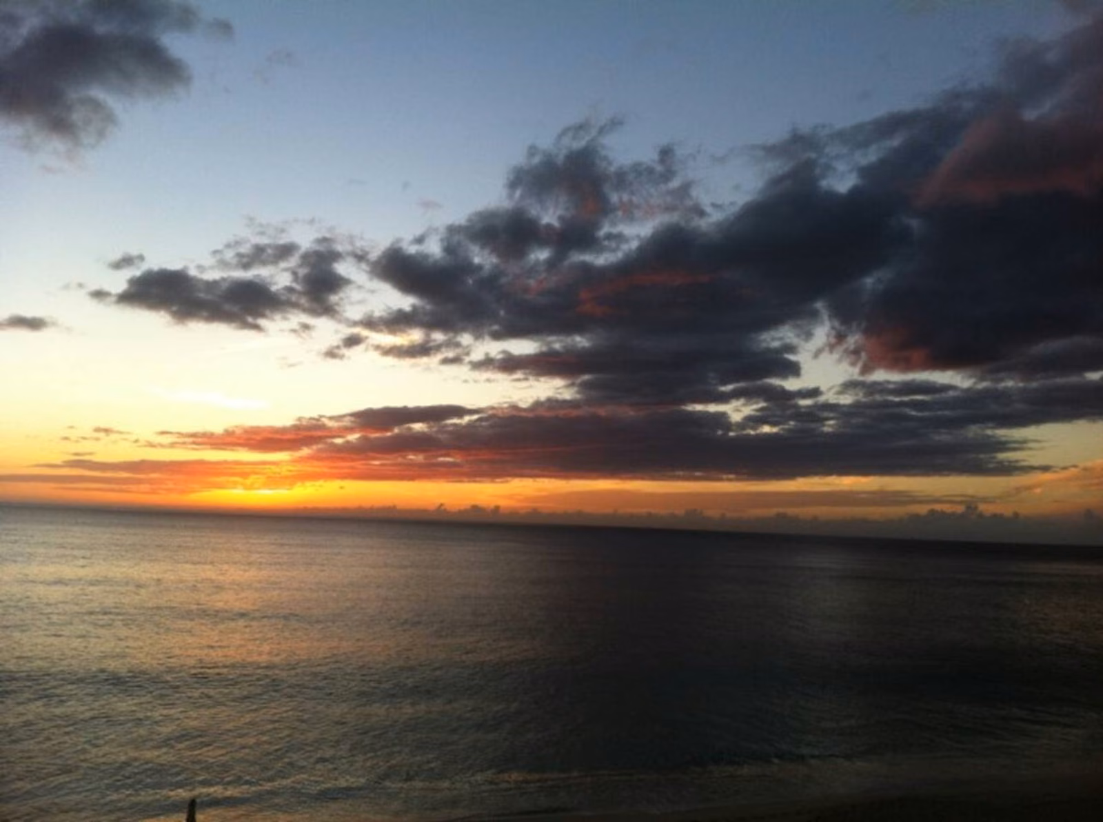 Dramatic orange and grey sunset clouds over the water off Makaha
